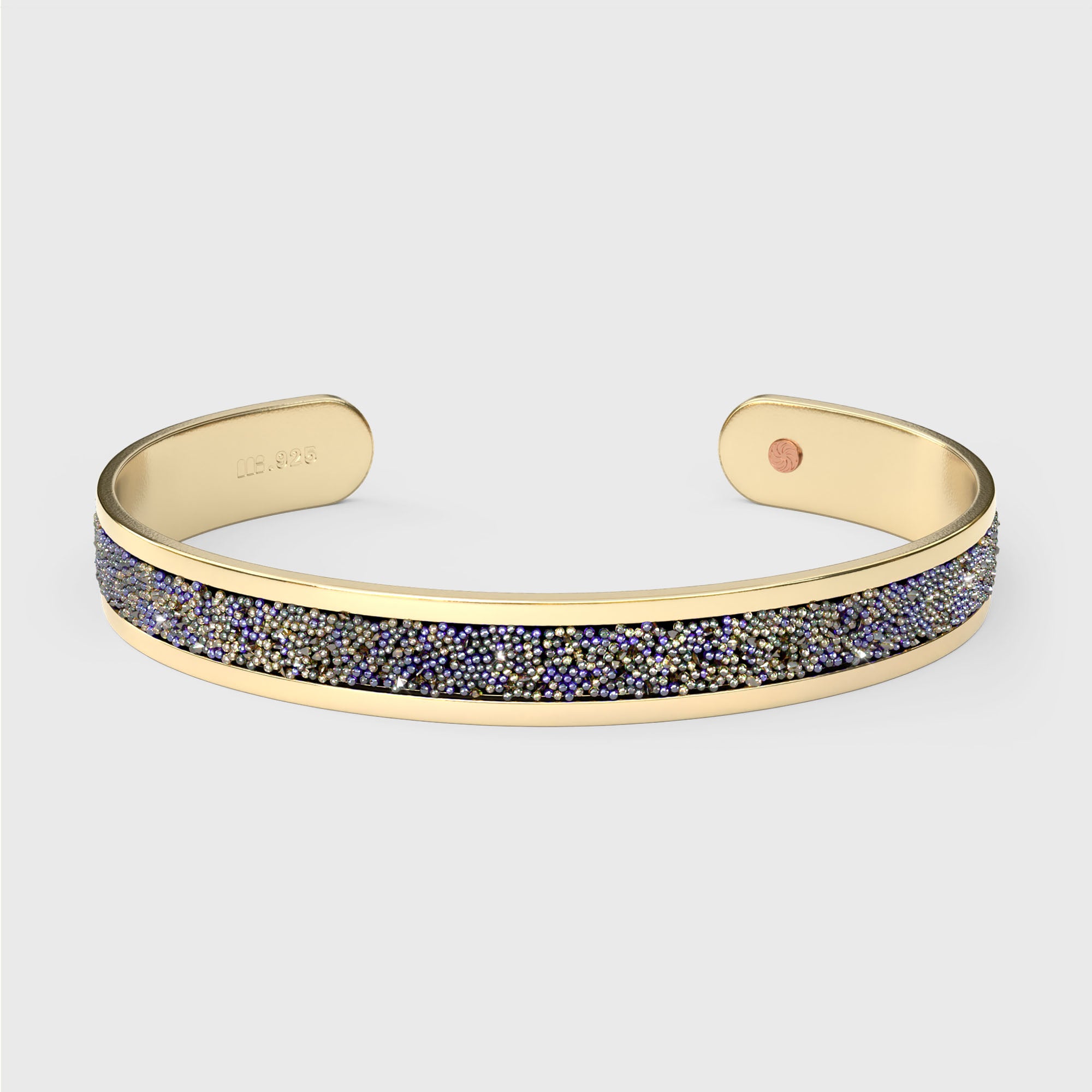 Close-up of SWAROVSKI® Heliotrope crystal fabric inlay on gold cuff, showing violet-blue sparkle and precision-cut texture.